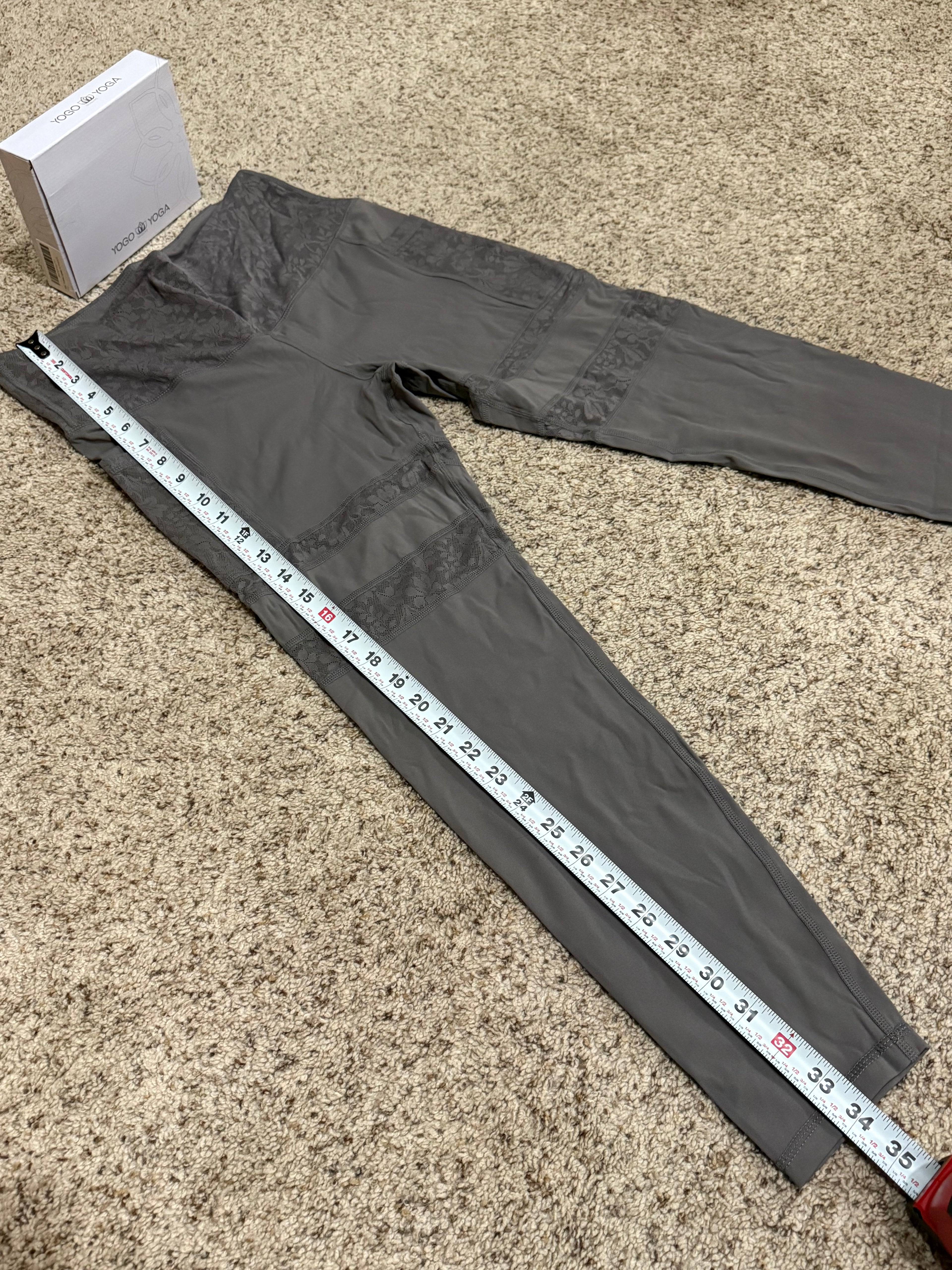 Gray pants with a measuring tape laid over them on a beige carpet