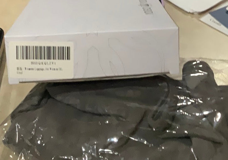 Gray garment in clear plastic wrap on a table with a box and papers.